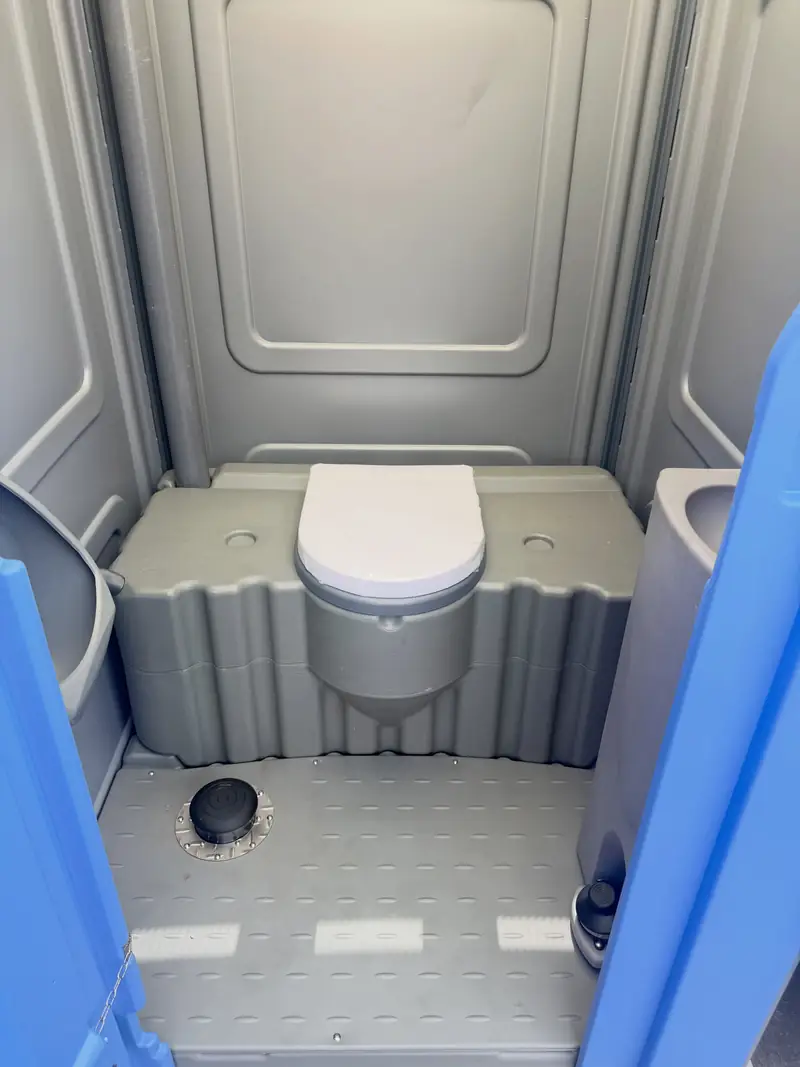 White flushing toilet inside a gray portable restroom