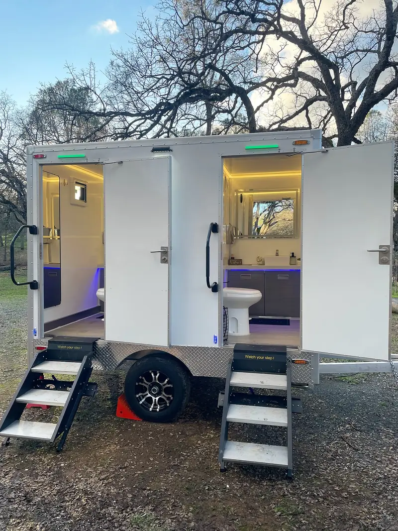 Two-room restroom trailer lit up in the evening