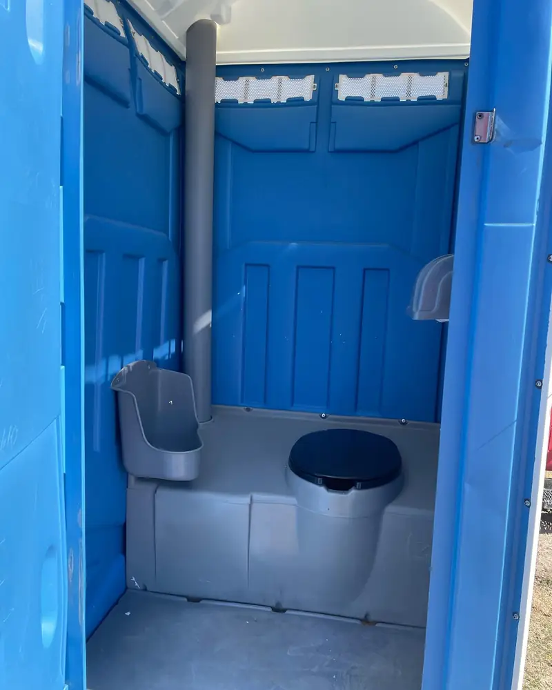 Inside a blue standard porta potty with toilet seat and urinal